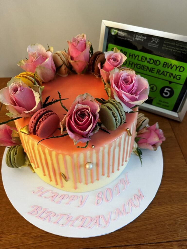 pink chocolate drip cake with fresh flowers and macaroons