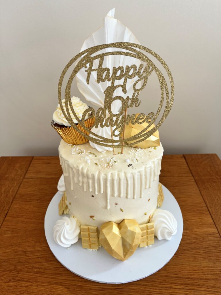 White chocolate drip cake with 16 cake topper meringues and chocolates