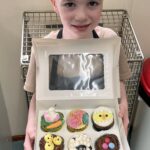 Child holding cupcakes