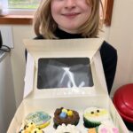 child holding cupcakes